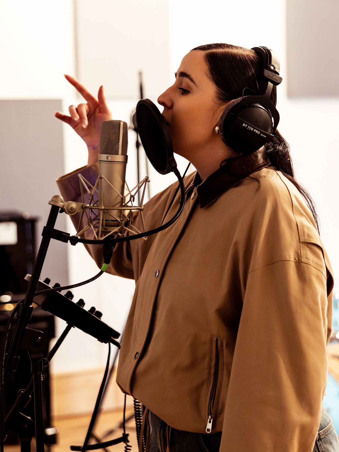 A musician with headphones and a mic in a studio.