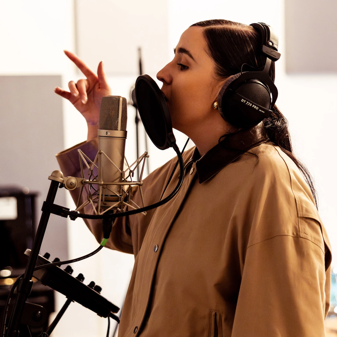 A musician with headphones and a mic in a studio.