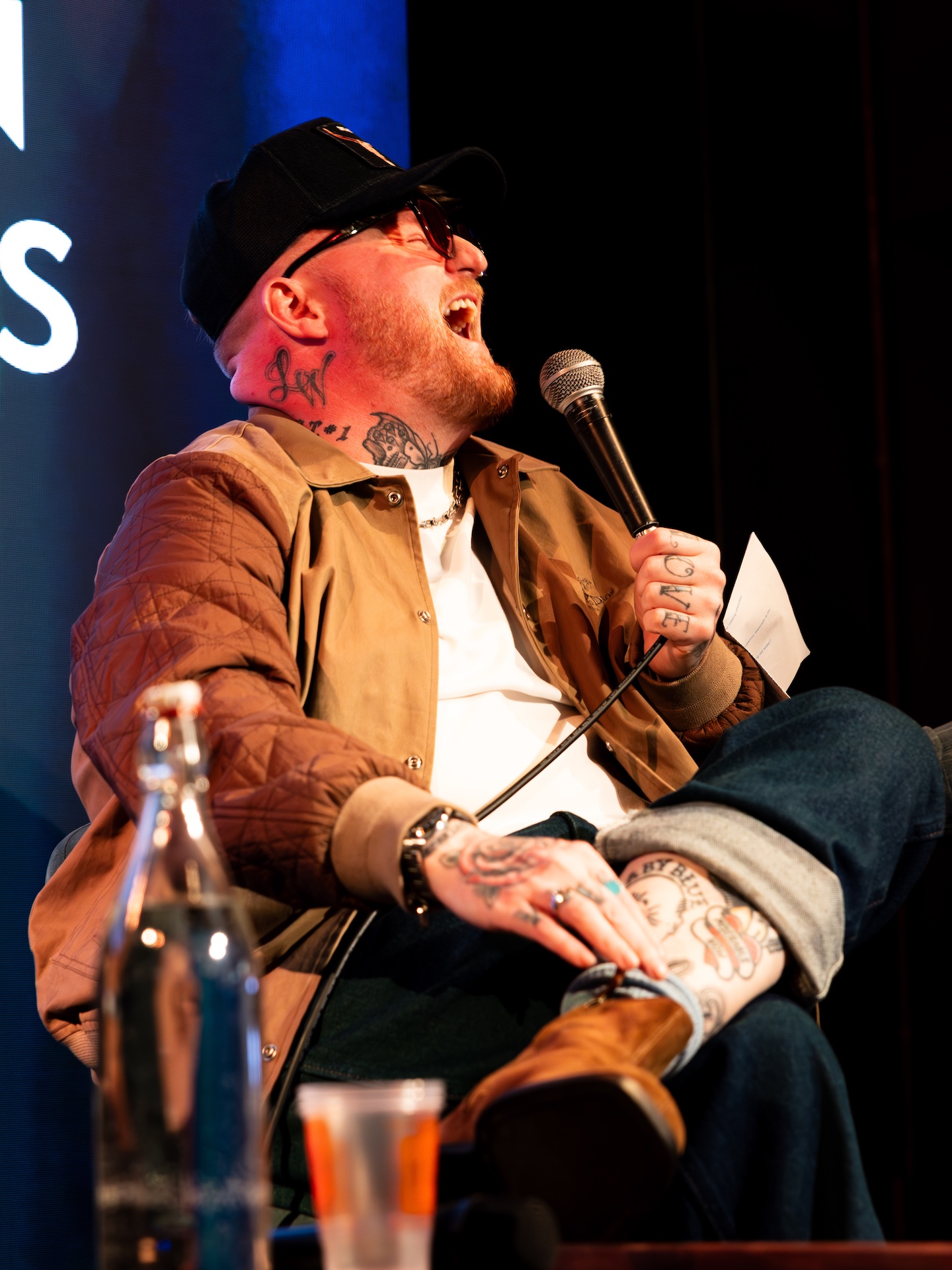 Lead singer of The Lottery Winners laughing and holding a mic during a panel.