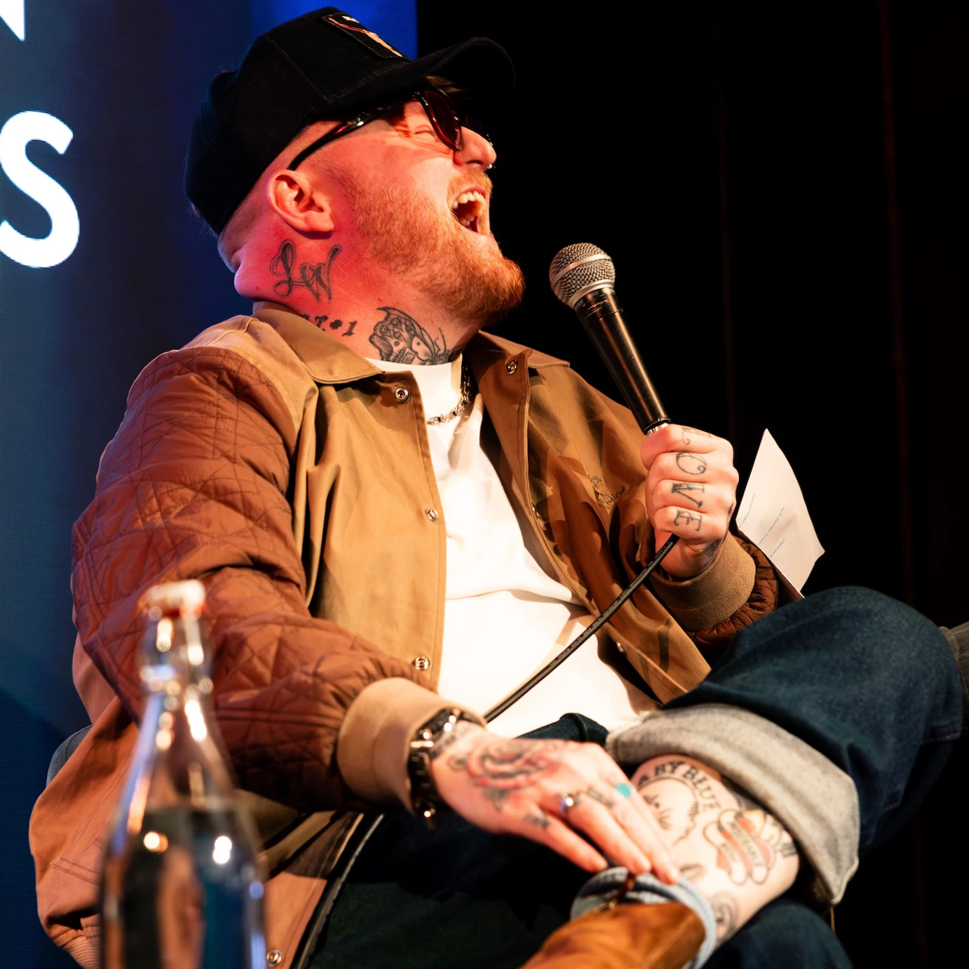 Lead singer of The Lottery Winners laughing and holding a mic during a panel.