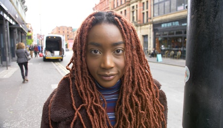 Princess Arinola (B!TEZ) stands on a Manchester street. She is looking directly into the camera.