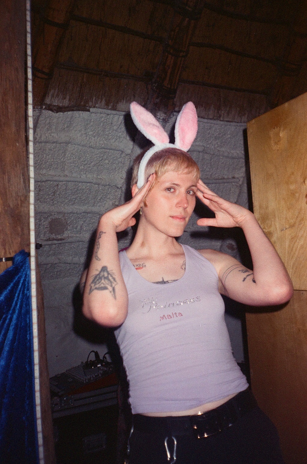 Lyn Vegas looking into the camera. They're wearing bunny ears with their fingers touching their temples.