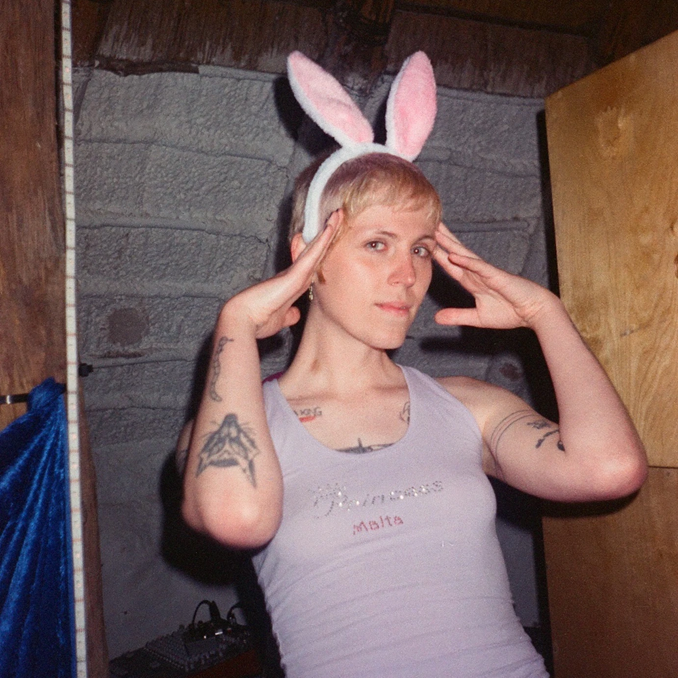 Lyn Vegas looking into the camera. They're wearing bunny ears with their fingers touching their temples.