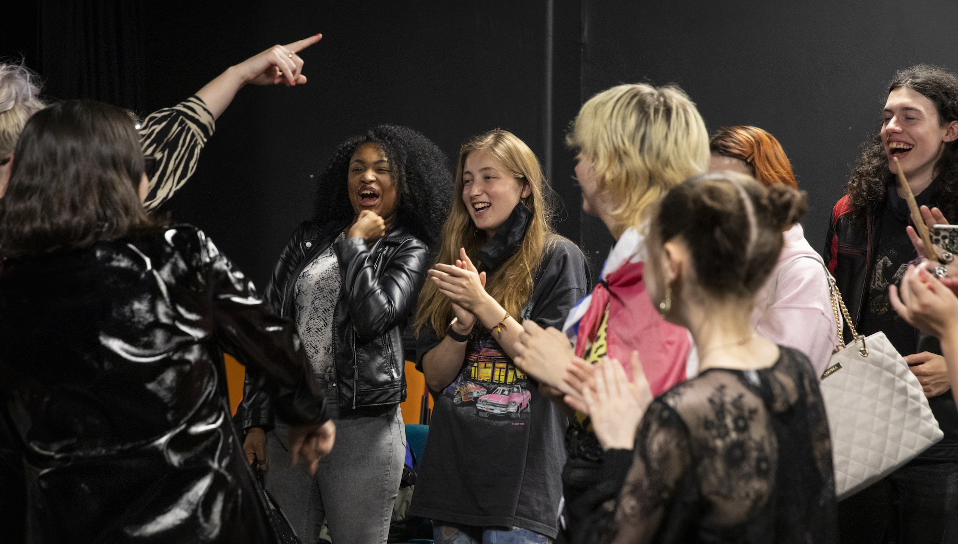 Participants and PINS cheering, laughing, smiling and clapping together backstage.
