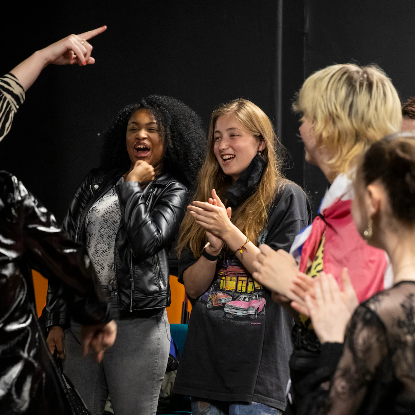 Participants and PINS cheering, laughing, smiling and clapping together backstage.
