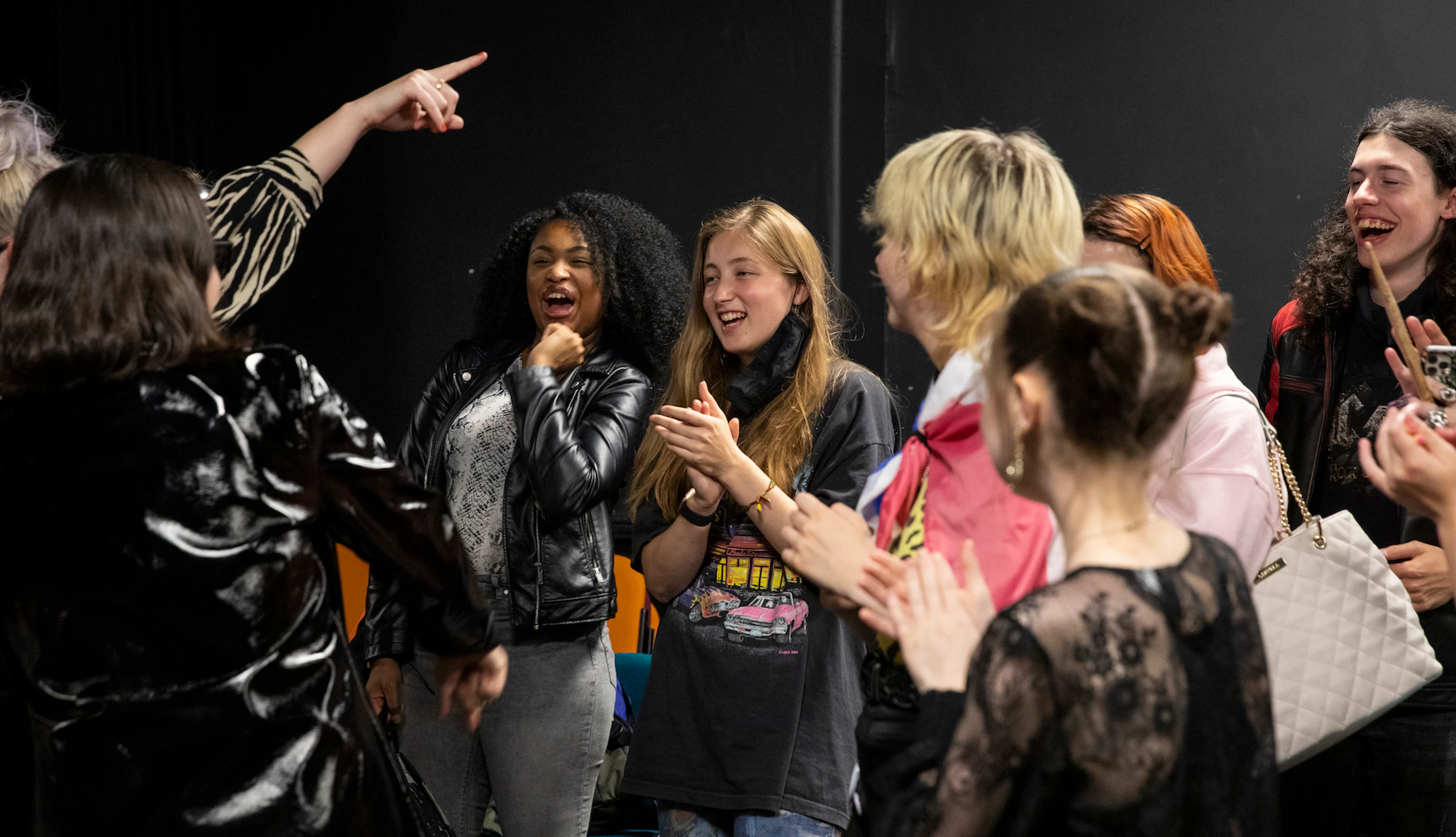 Participants and PINS cheering, laughing, smiling and clapping together backstage.