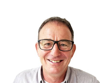 A professional headshot of Andy Lovatt. He is smiling into the camera and is wearing thick black glasses.