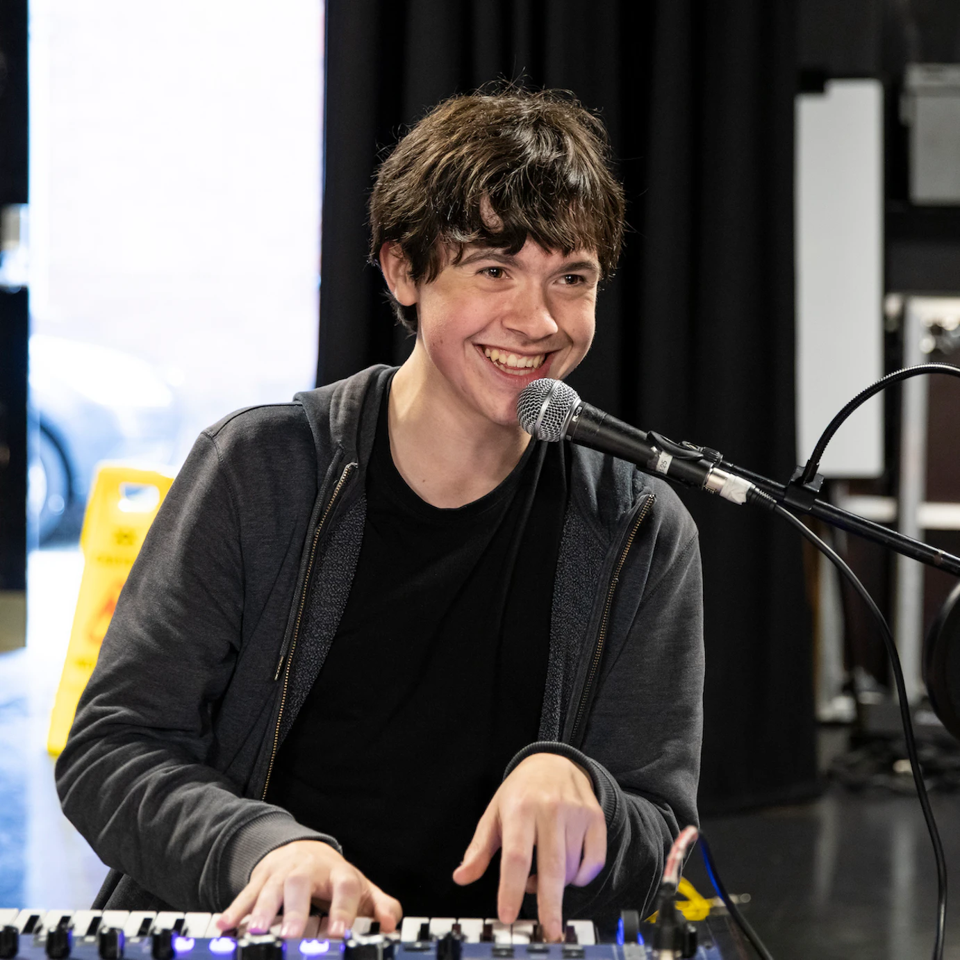A participant playing keyboard and smiling broadly into a microphone.