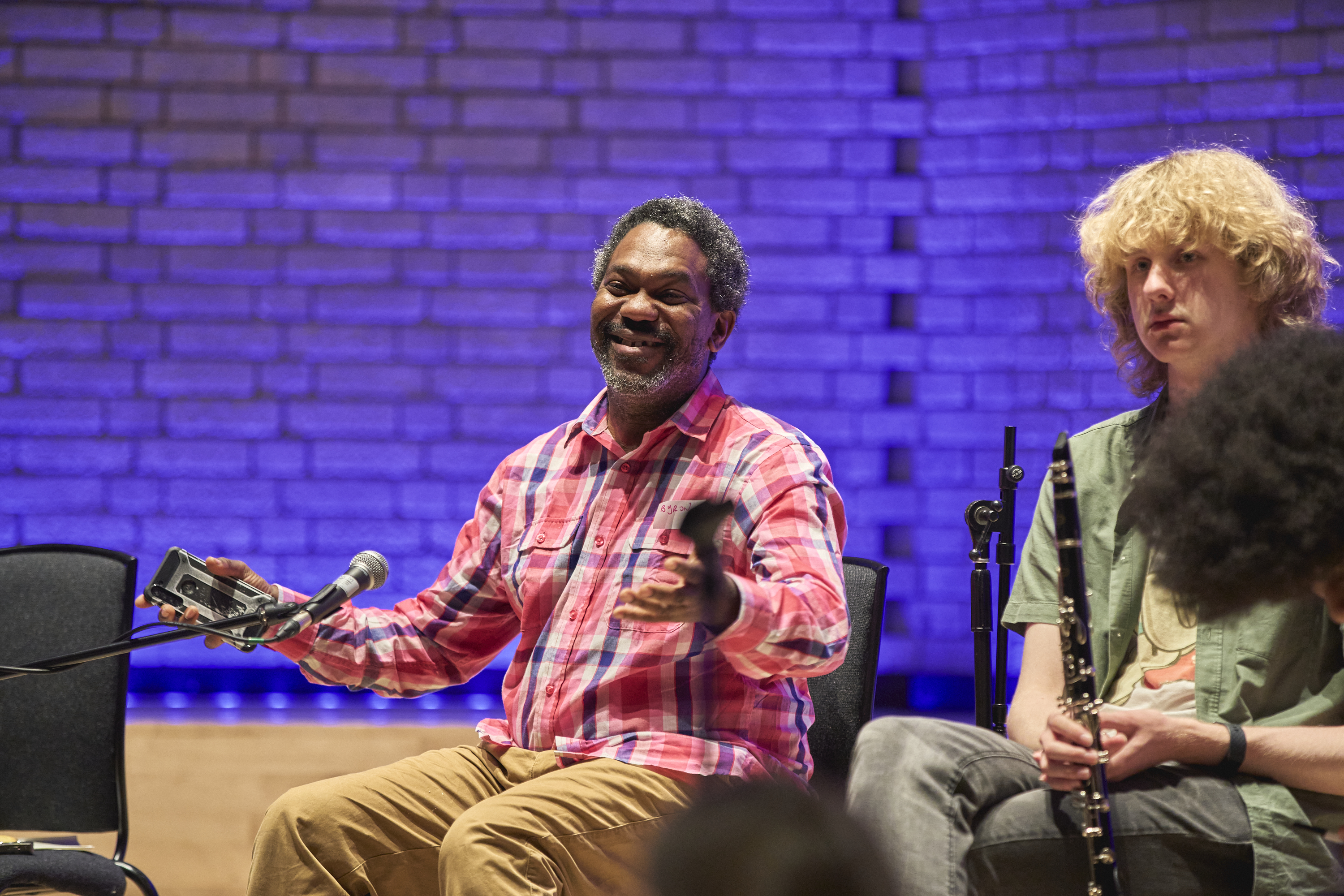 Byron Wallen sat next to a young musician smiling widely with open arms.