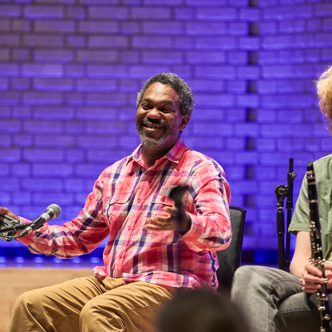 Byron Wallen sat next to a young musician smiling widely with open arms.