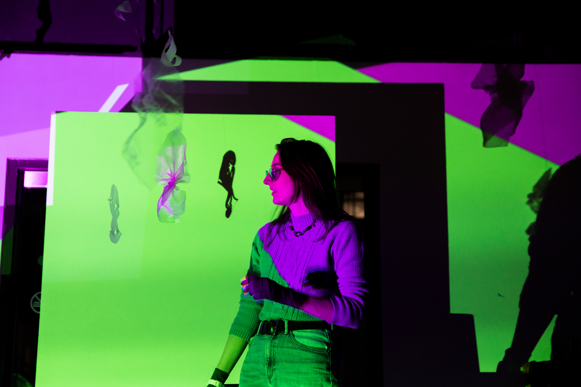Rosie Woolaghan at the Self, Sense, Space installation, illuminated by green and purple projections.