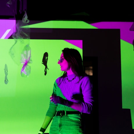 Rosie Woolaghan at the Self, Sense, Space installation, illuminated by green and purple projections.