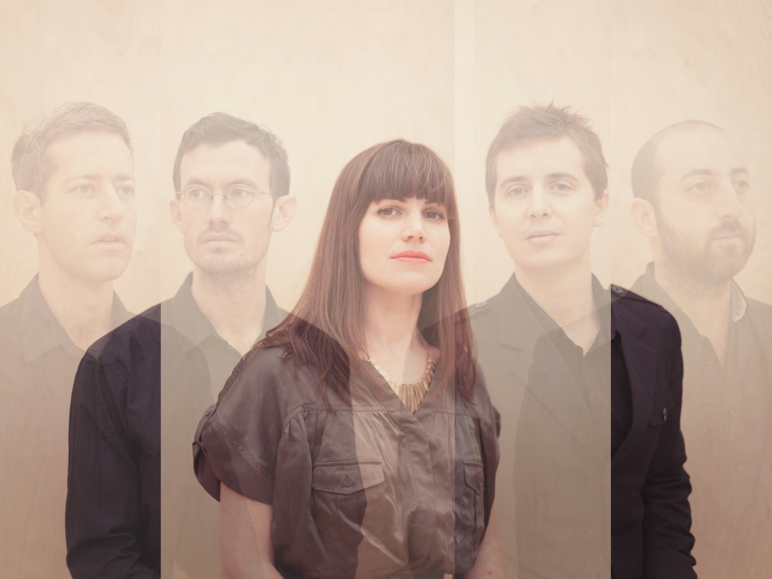 The band Firefly Burning wearing black, against a cream background, all looking in different directions.