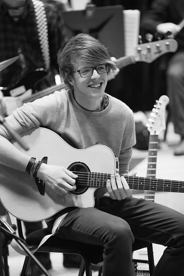 A musician smiling with a guitar.