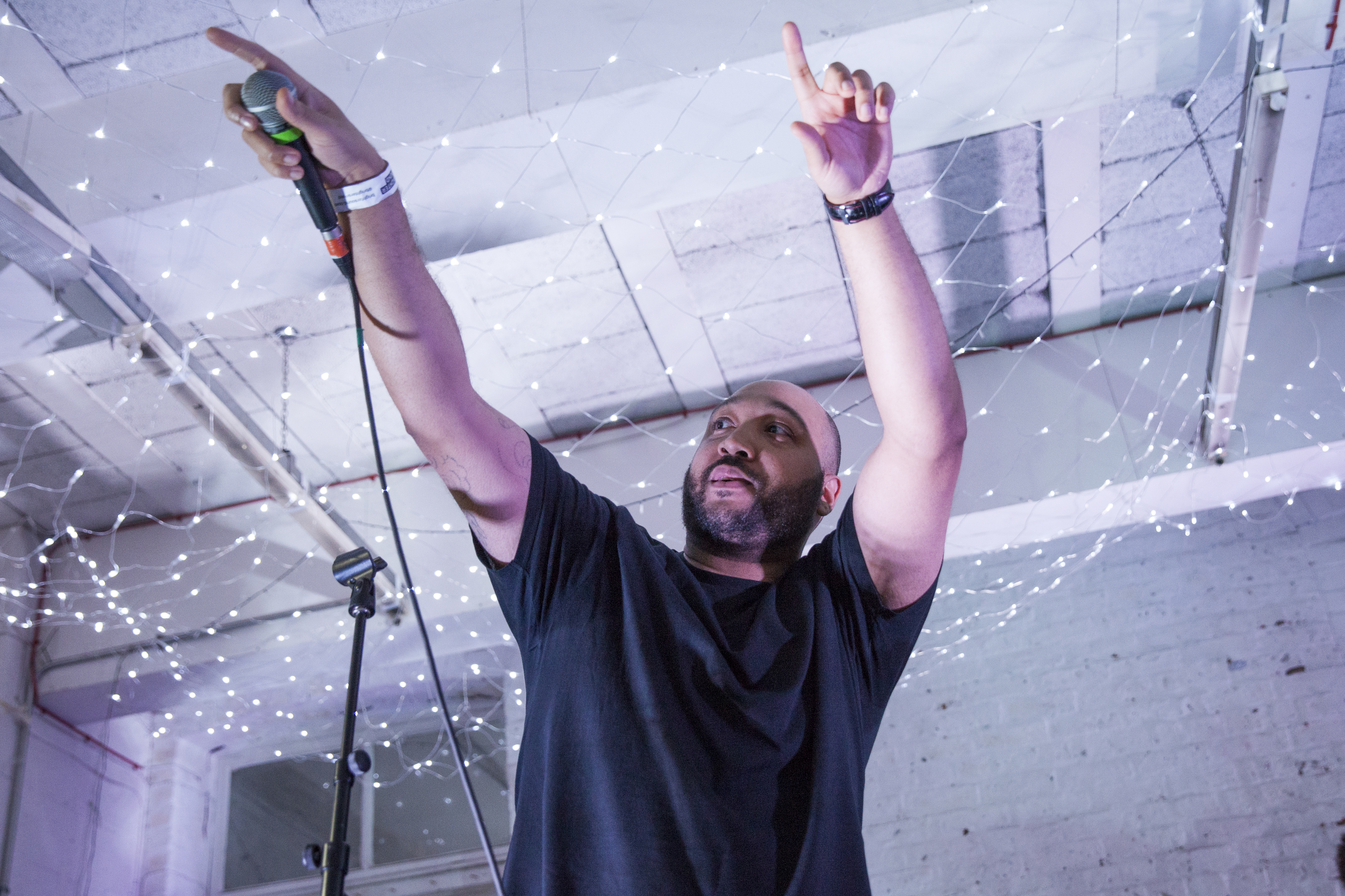 A person is on stage holding a microphone and points out to the audience, encouraging them to join in.