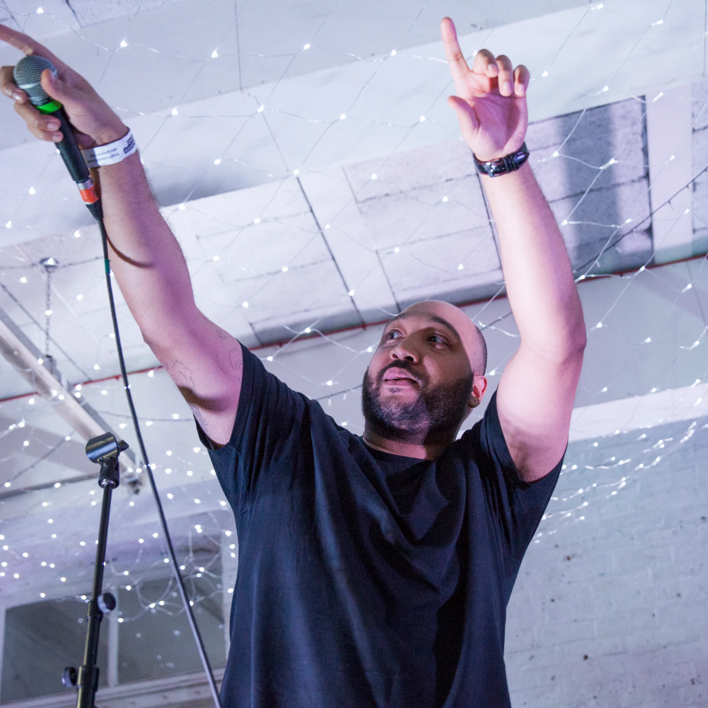A person is on stage holding a microphone and points out to the audience, encouraging them to join in.