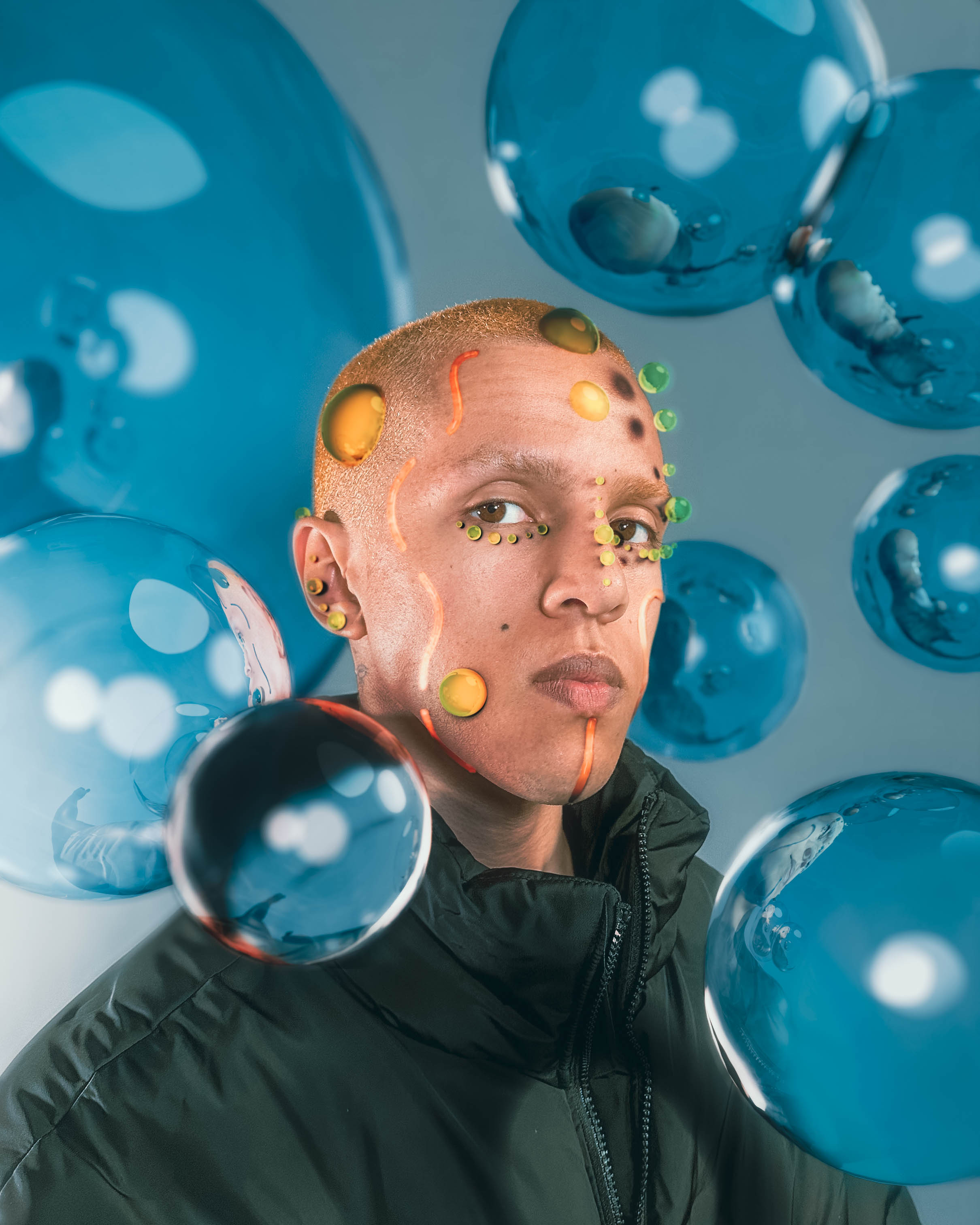 is33n is covered in digitally created bubbles of yellow and green, and orange lines. They are surrounded by blue bubbles and are looking into the camera.