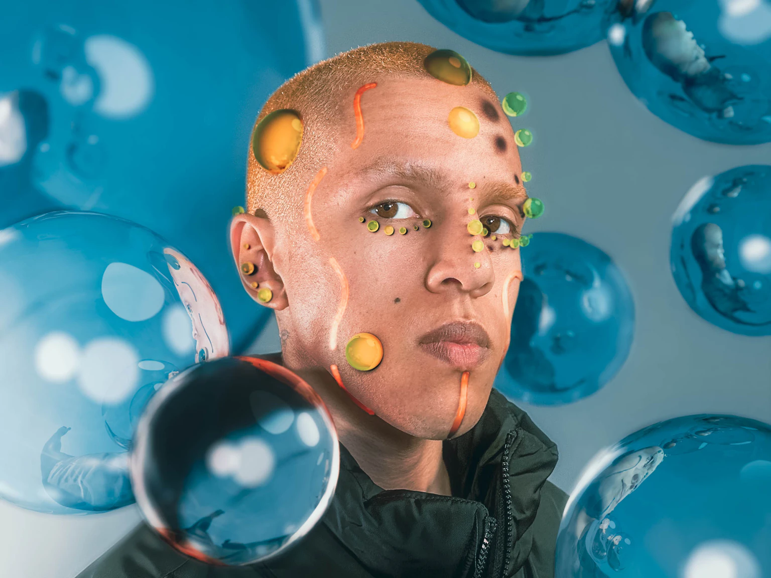 is33n is covered in digitally created bubbles of yellow and green, and orange lines. They are surrounded by blue bubbles and are looking into the camera.