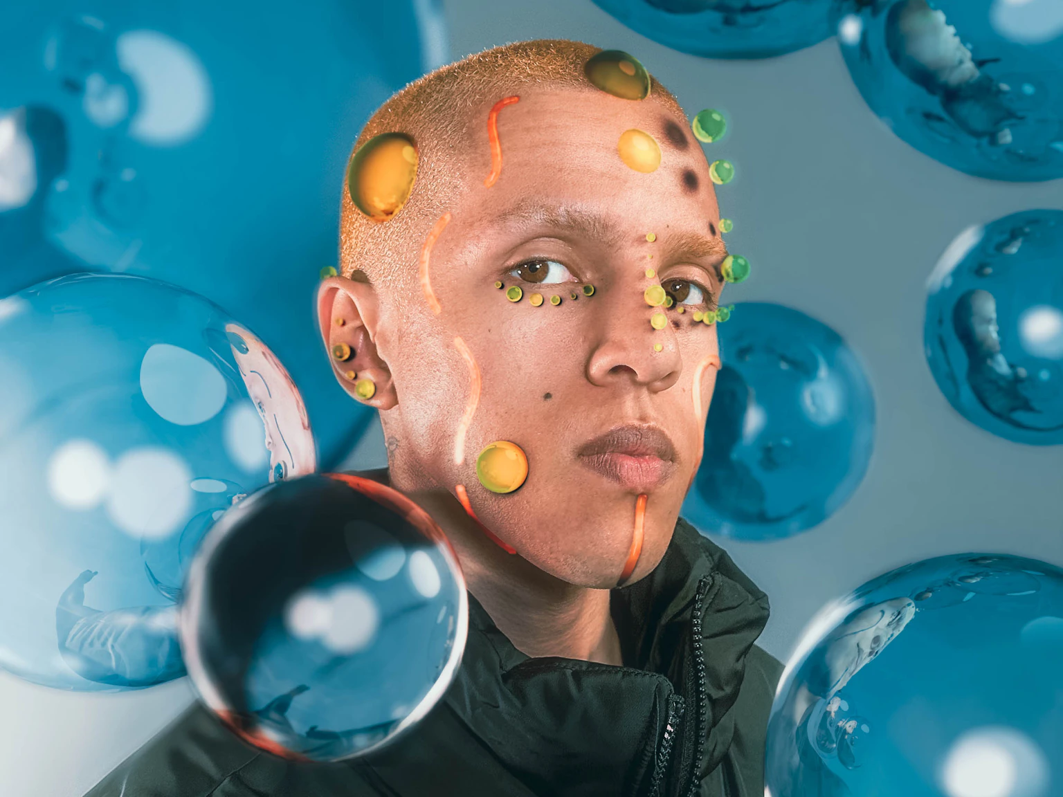 is33n is covered in digitally created bubbles of yellow and green, and orange lines. They are surrounded by blue bubbles and are looking into the camera.