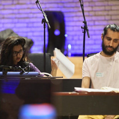 A young musician and Balraj Samrai sat behind a piano and a keyboard respectively looking down at the keys.