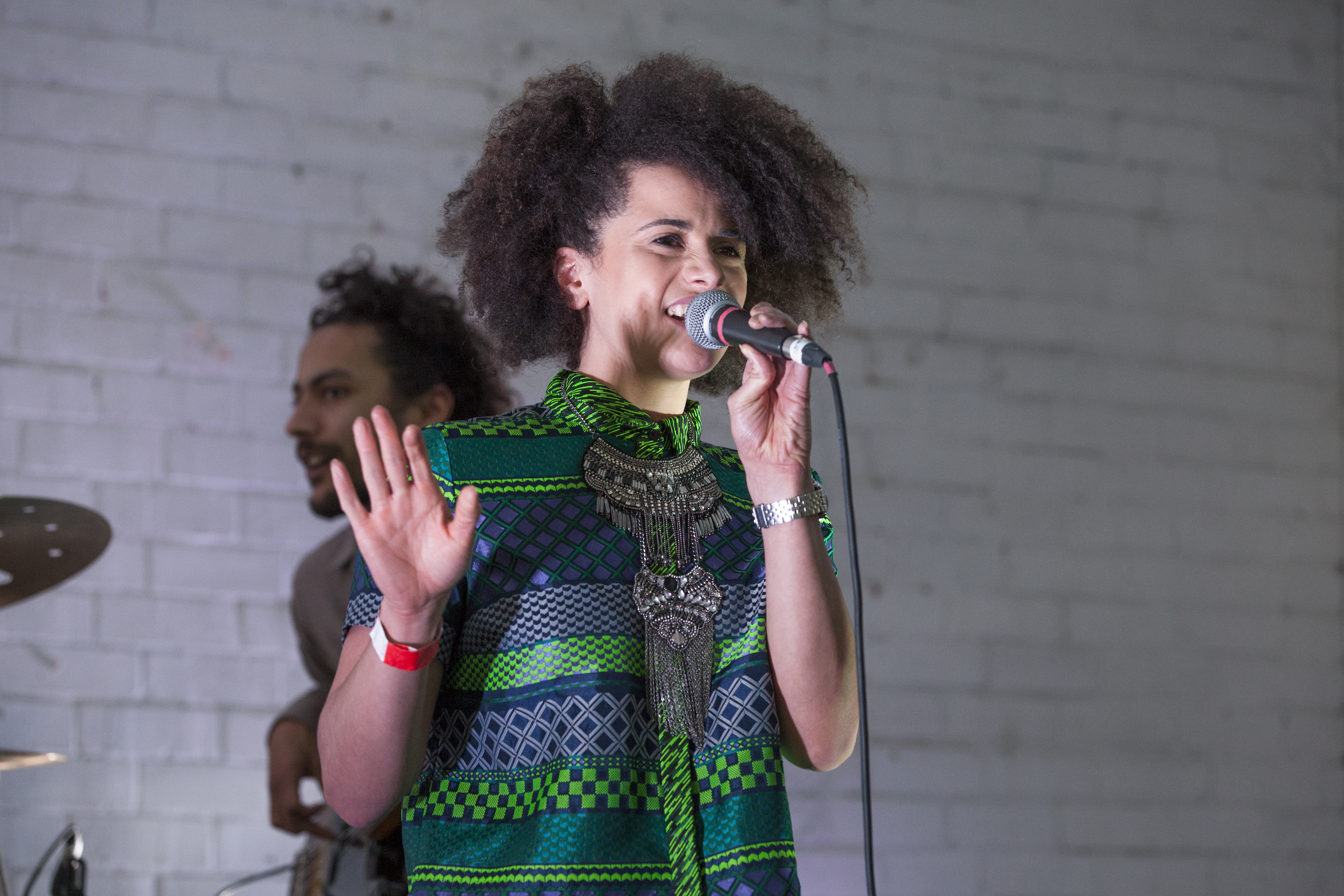 Close up shot of Chesqua singing into a microphone with the bassist playing in the background.