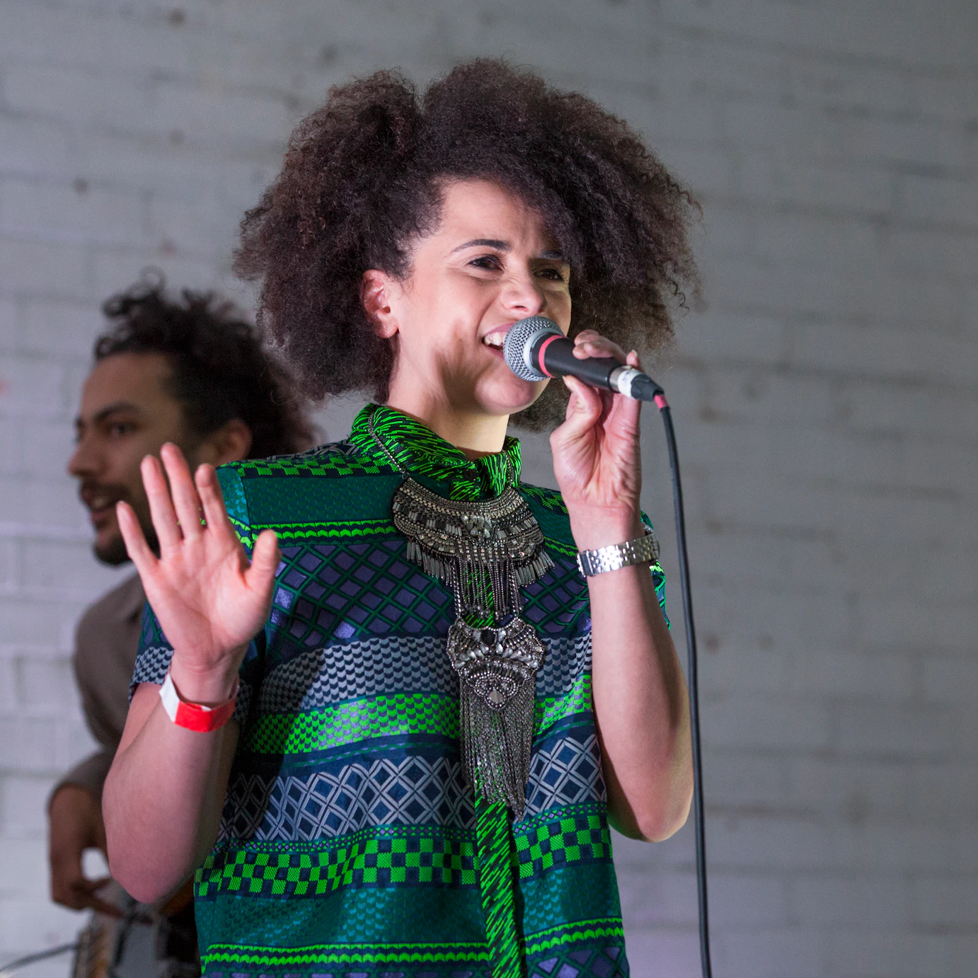 Close up shot of Chesqua singing into a microphone with the bassist playing in the background.