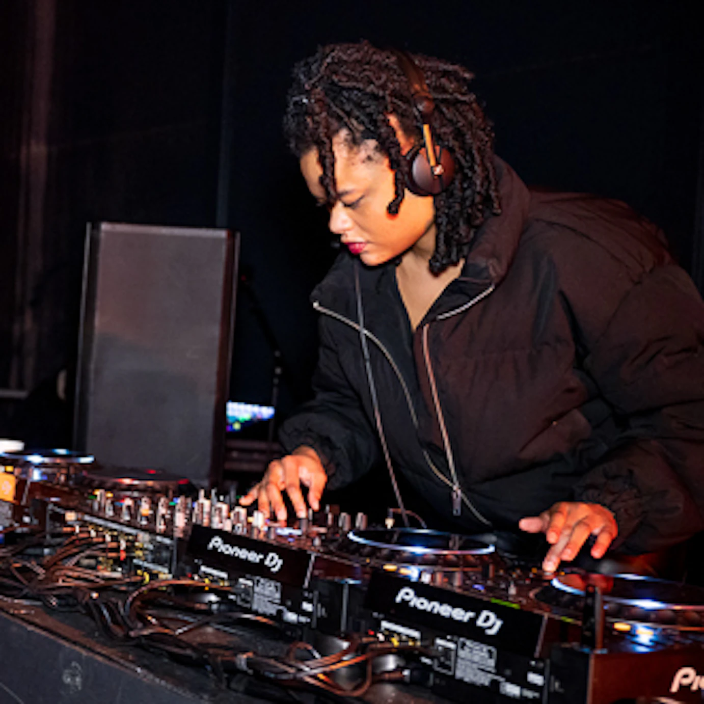 DJ Shannen SP on the decks. To the left is a Brighter Sound lightbox in the shape of our old logo placed on top of a flight case.