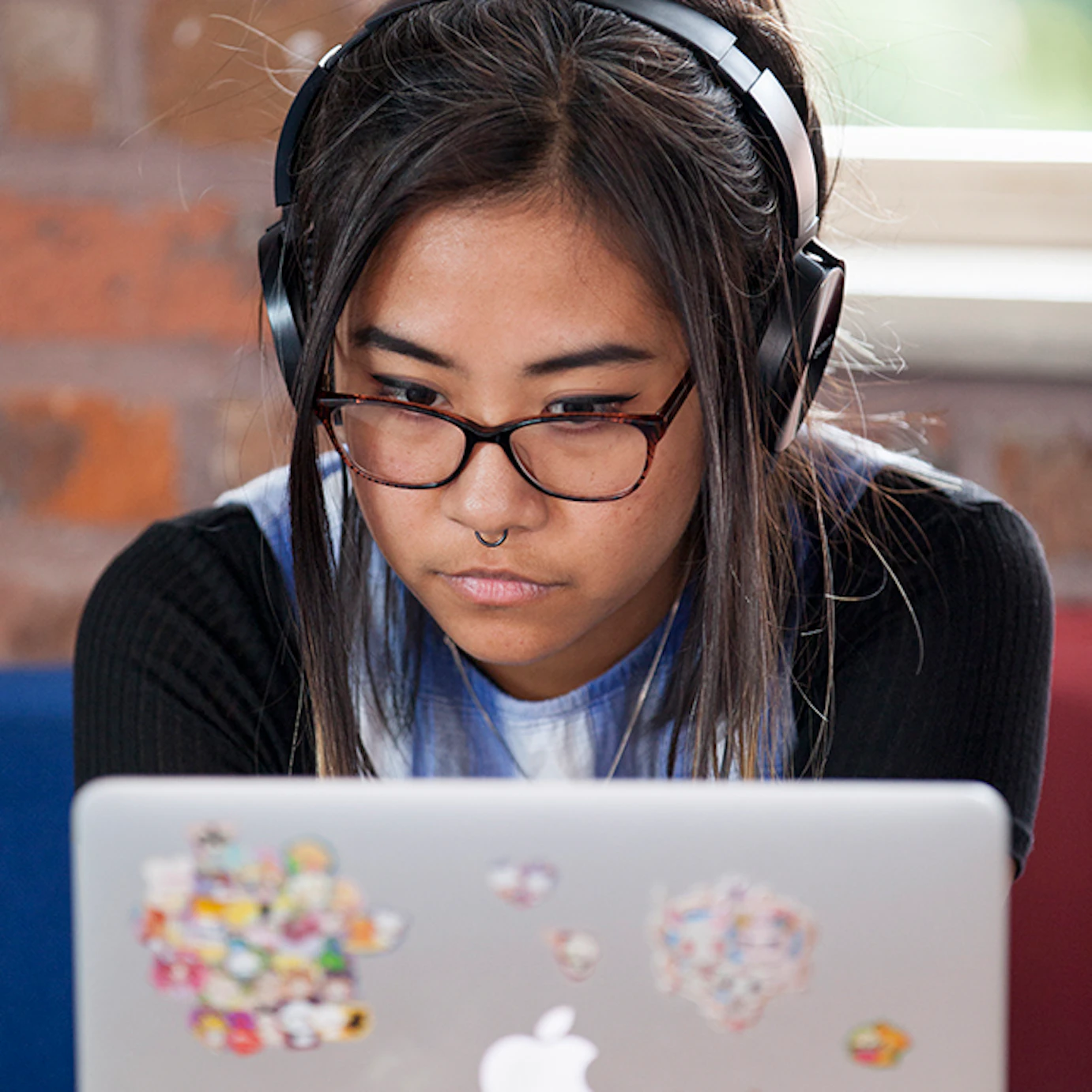 A visual artist on a laptop with headphones in.