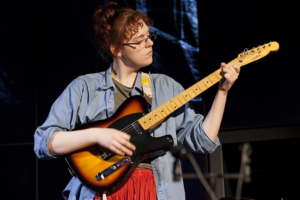 A musician playing guitar on stage.