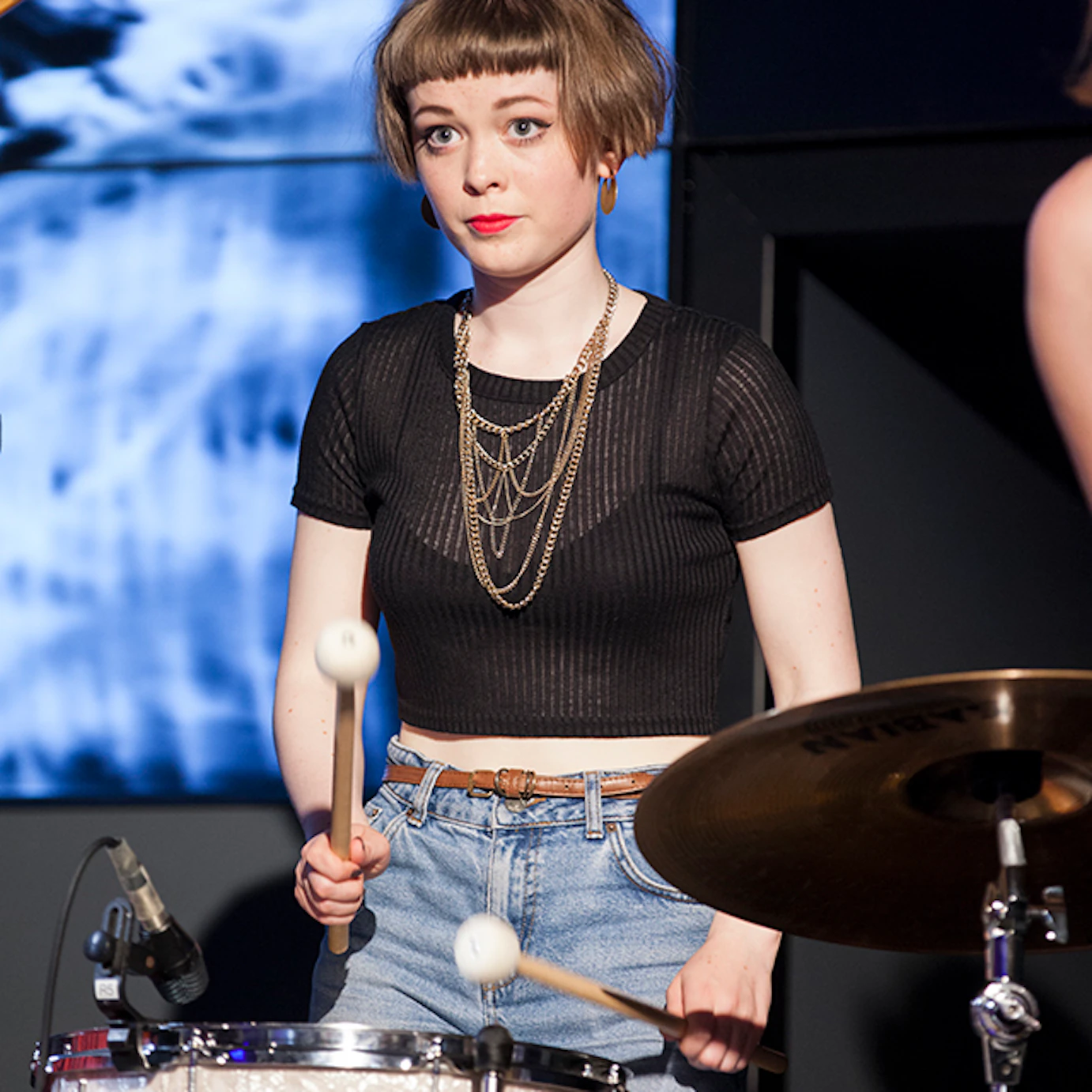 A musician playing drums in front of projected visuals.