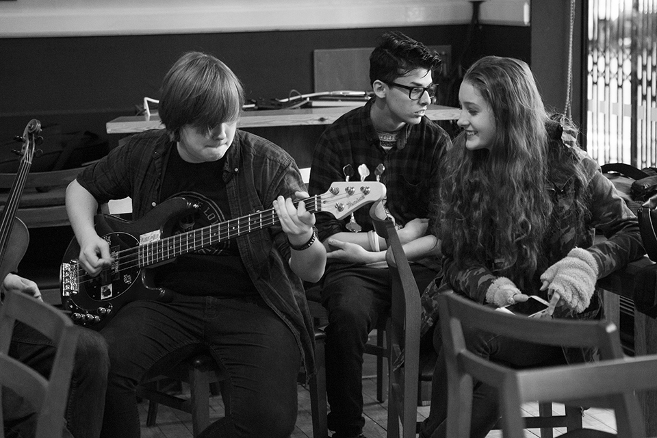 Musicians gathered. One is playing bass.