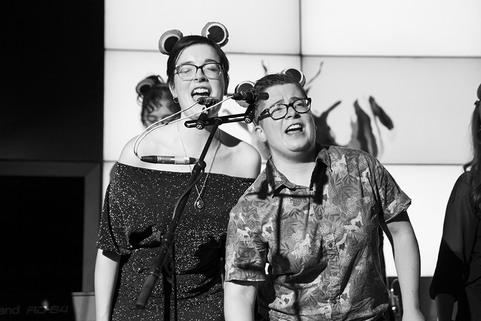 Two musicians singing with frog ears on.