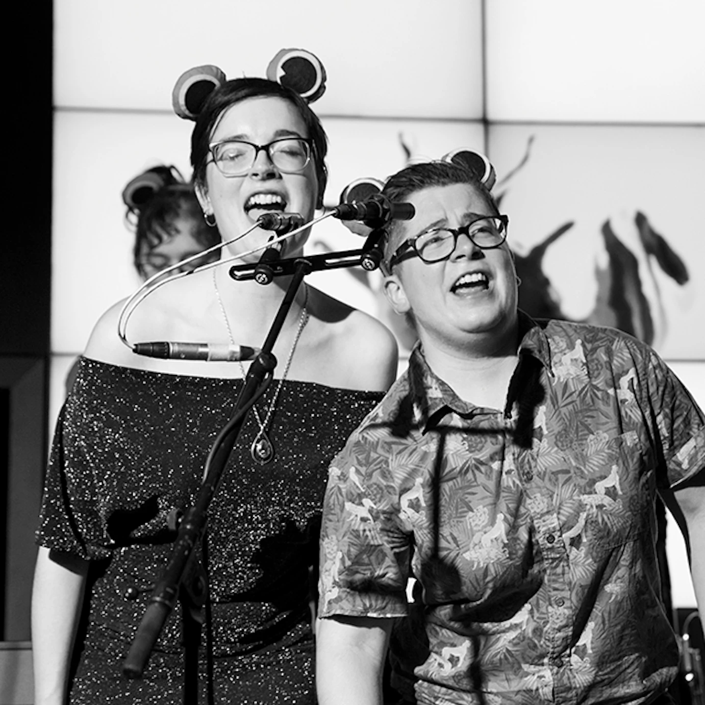 Two musicians singing with frog ears on.