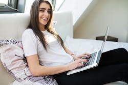 student with laptop on bed