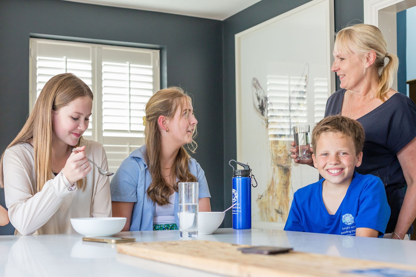 two girls and boy eating breakfast in kitchen