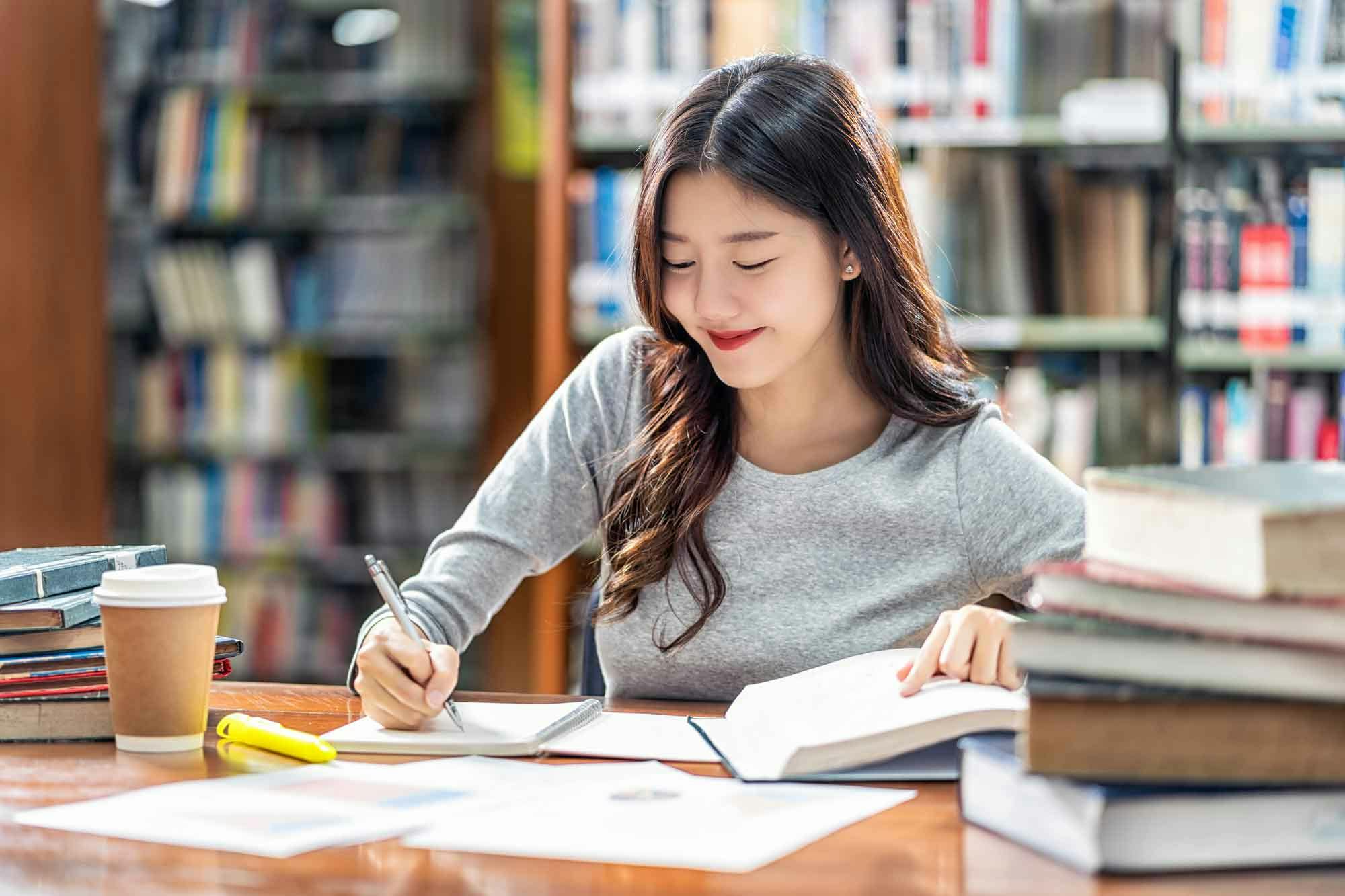 Girl writing and studying in library