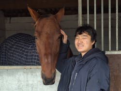 a young boy petting a horse in a stable