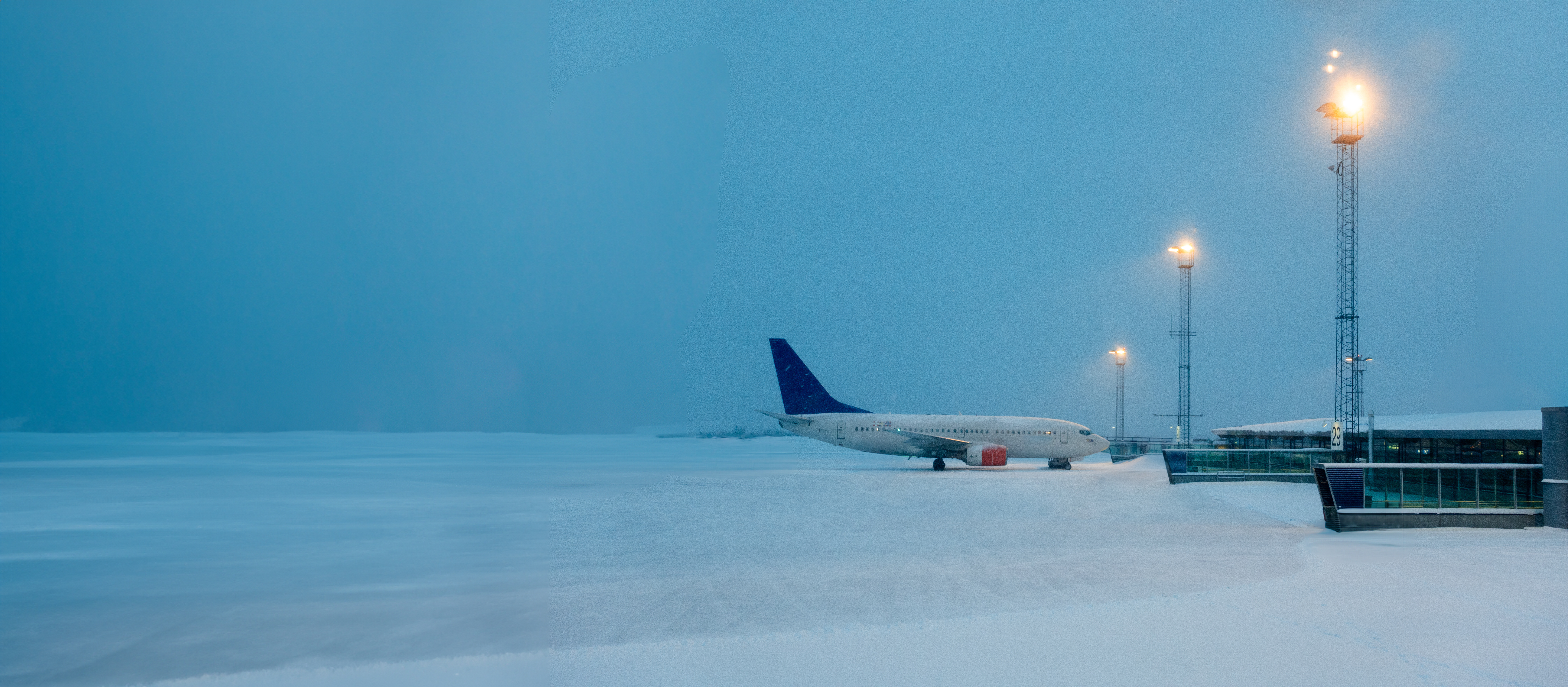 an empty snow-covered airport with only one plane on the runway