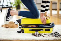 student kneeling on suitcase