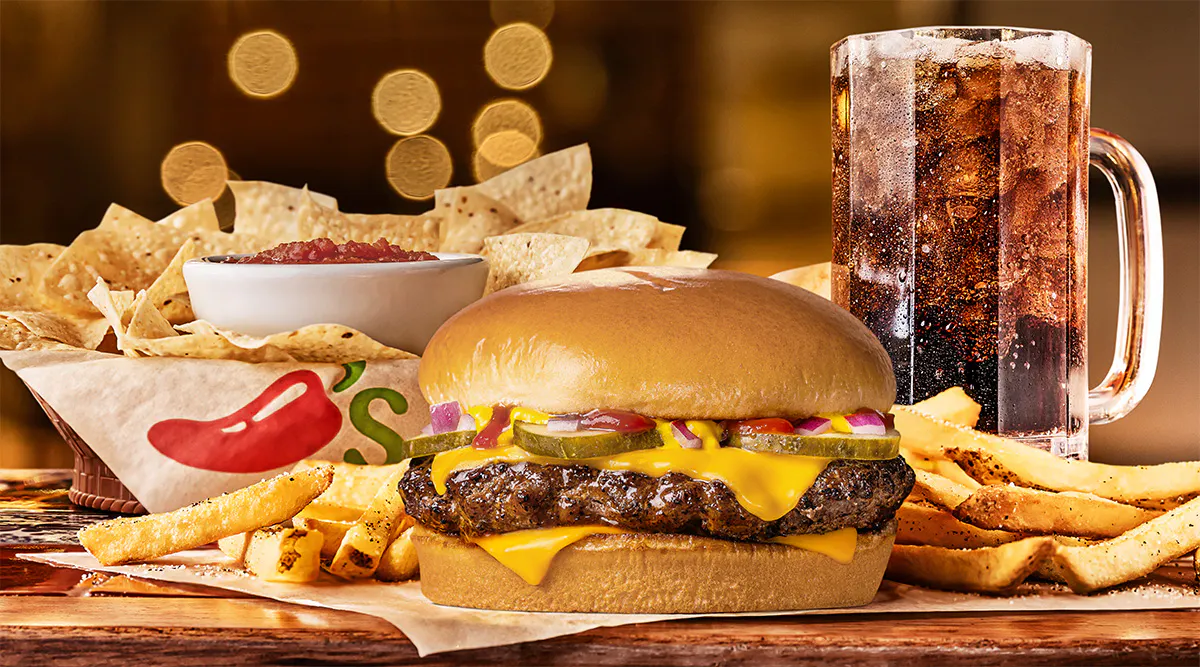 A Chili’s burger served with fries, chips, salsa and a drink