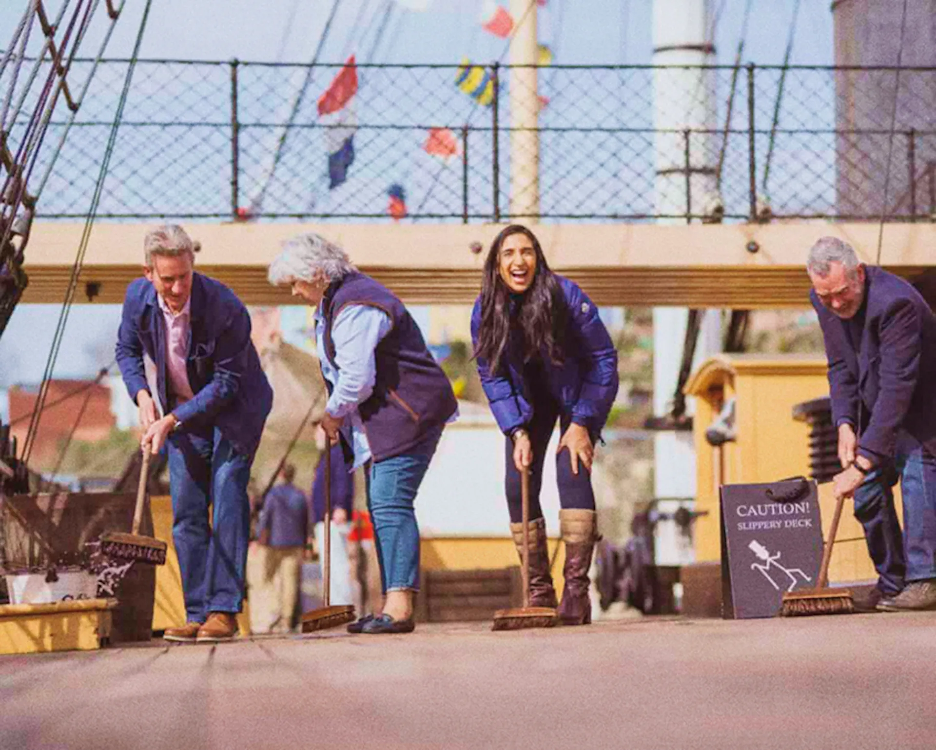 4 adults "scrubbing" the weather deck of the ship.