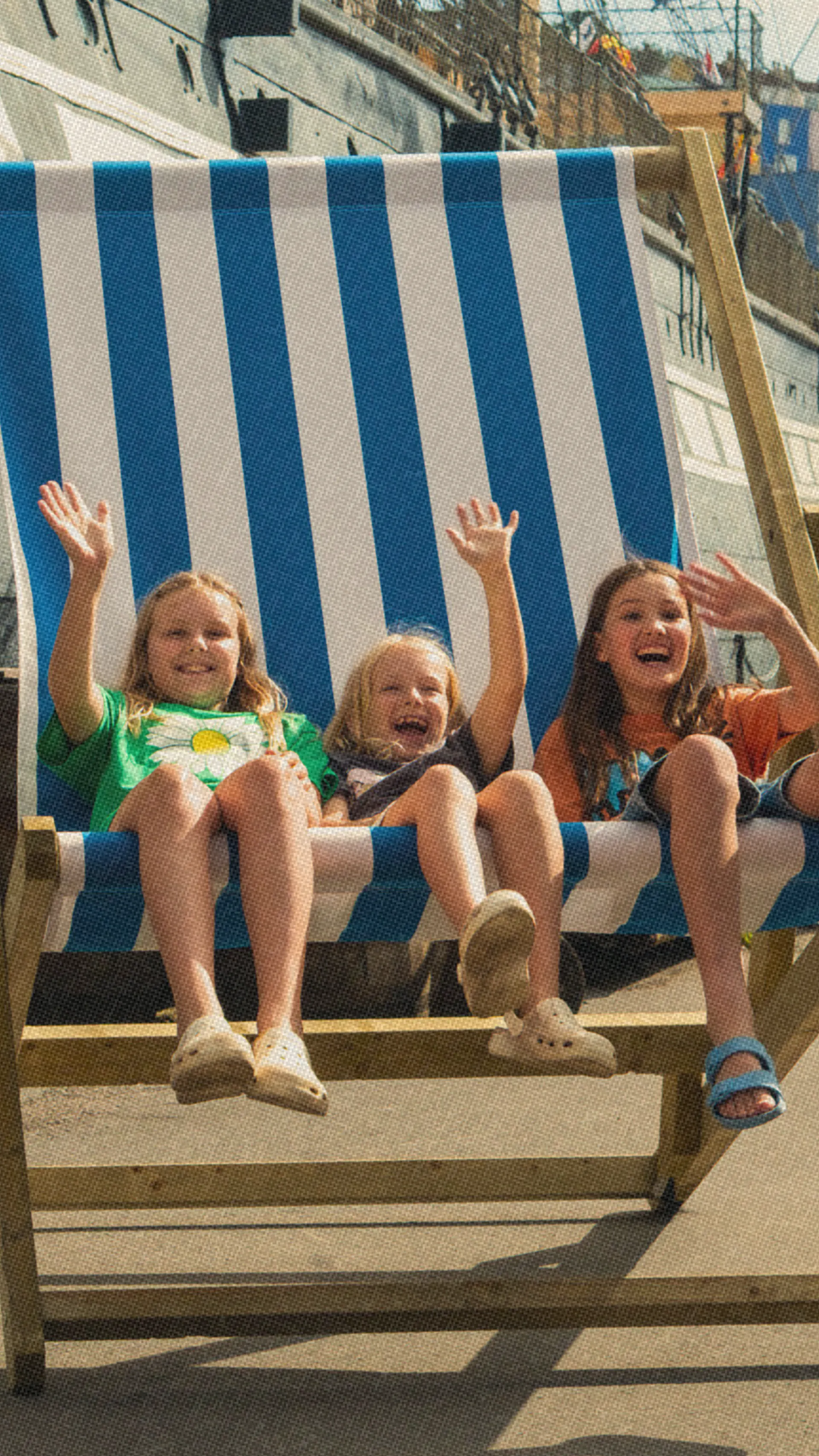 Three children on a big deck chair in front of the SS Great Britain at Bristol Dockyards 