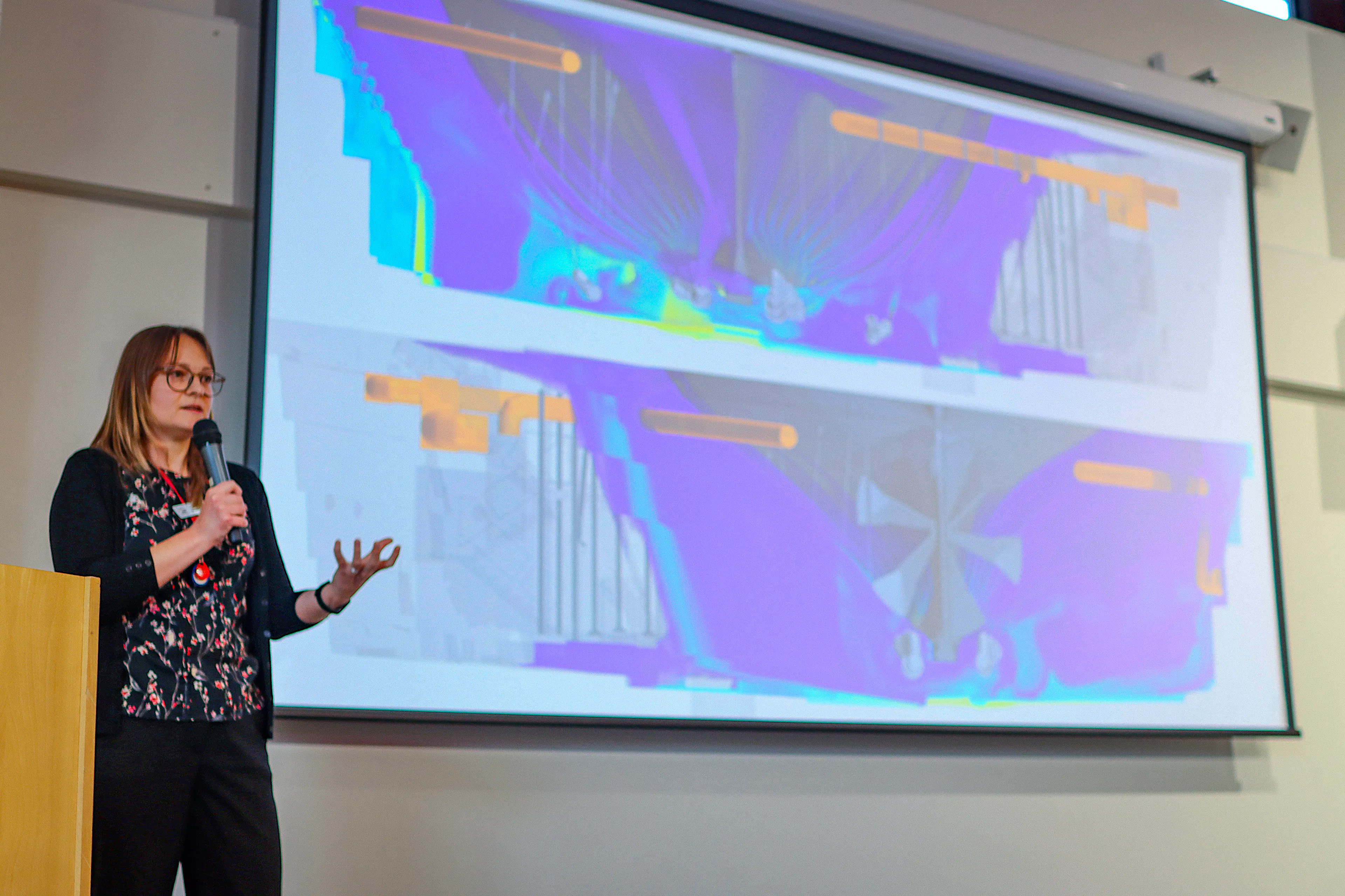 Ship's scientist giving a talk with a heat map on the slideshow behind her