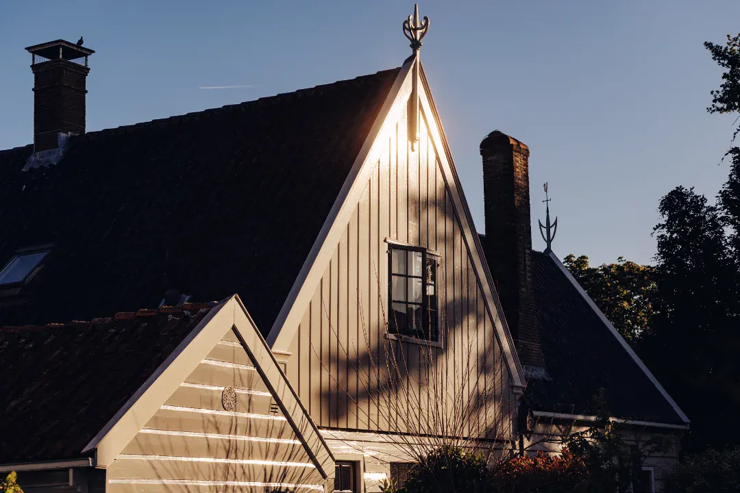 Opkomende zon reflecteert in grijzen houten huis in Broek in Waterland