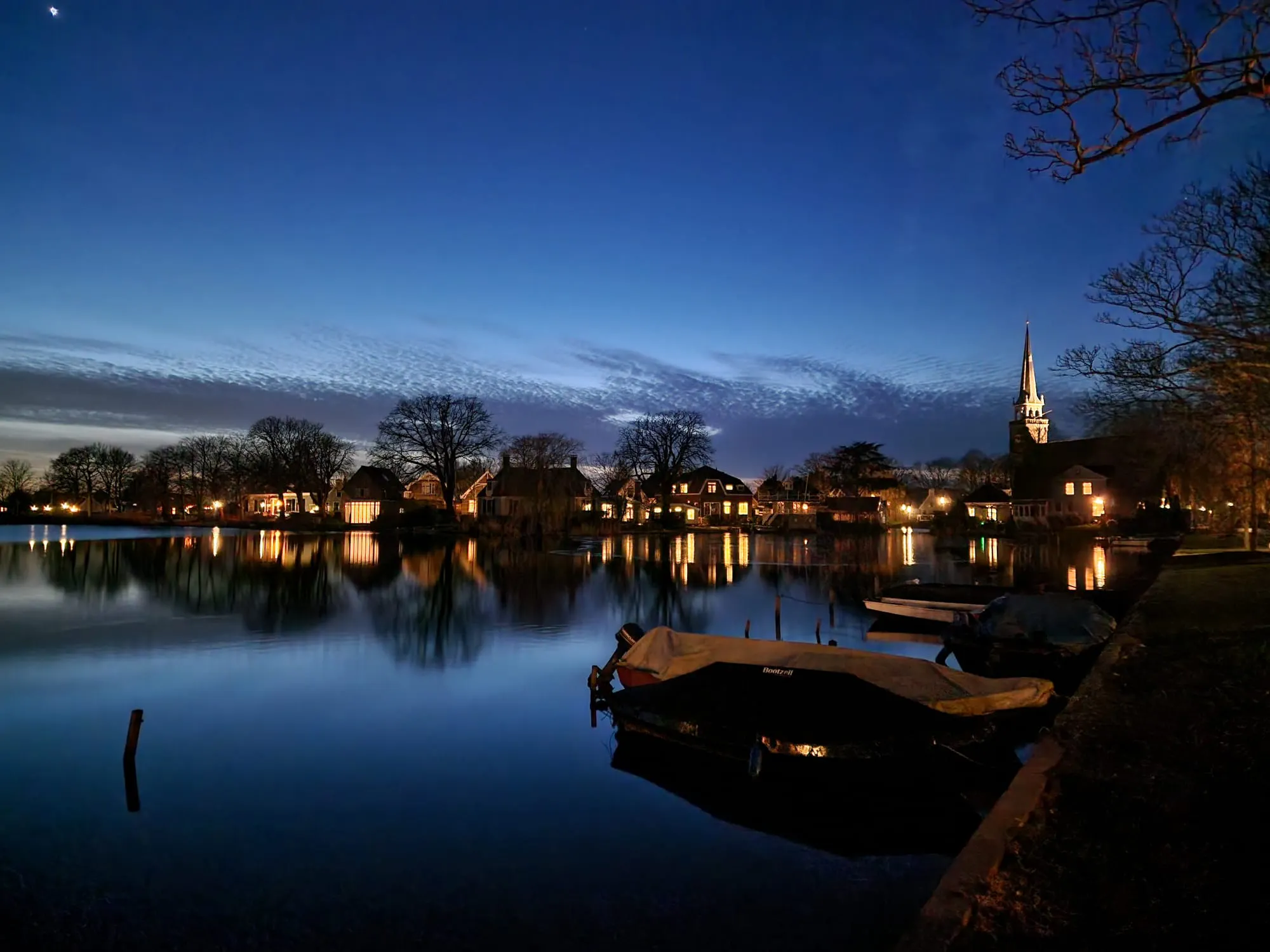 De Sint-Nicolaaskerk in Broek in Waterland in de avond, met boten aan het water