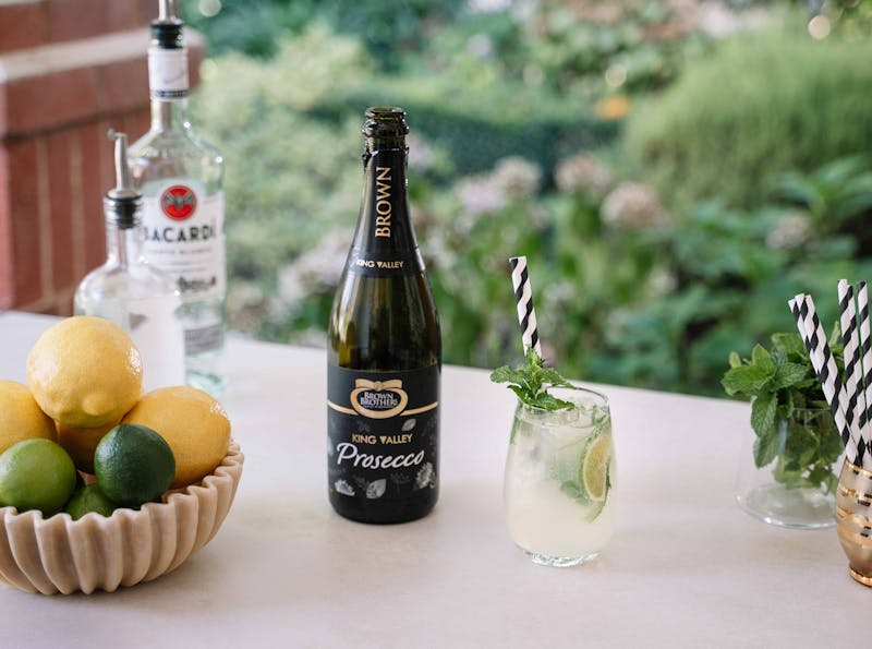 Prosecco Mojito cocktail in a glass alongside a bottle of Brown Brothers Prosecco