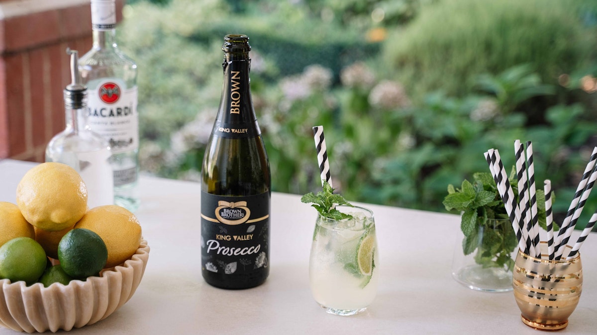 Prosecco Mojito cocktail in a glass alongside a bottle of Brown Brothers Prosecco