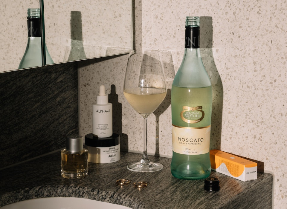 Adore Beauty products and Brown Brothers Moscato on bathroom vanity