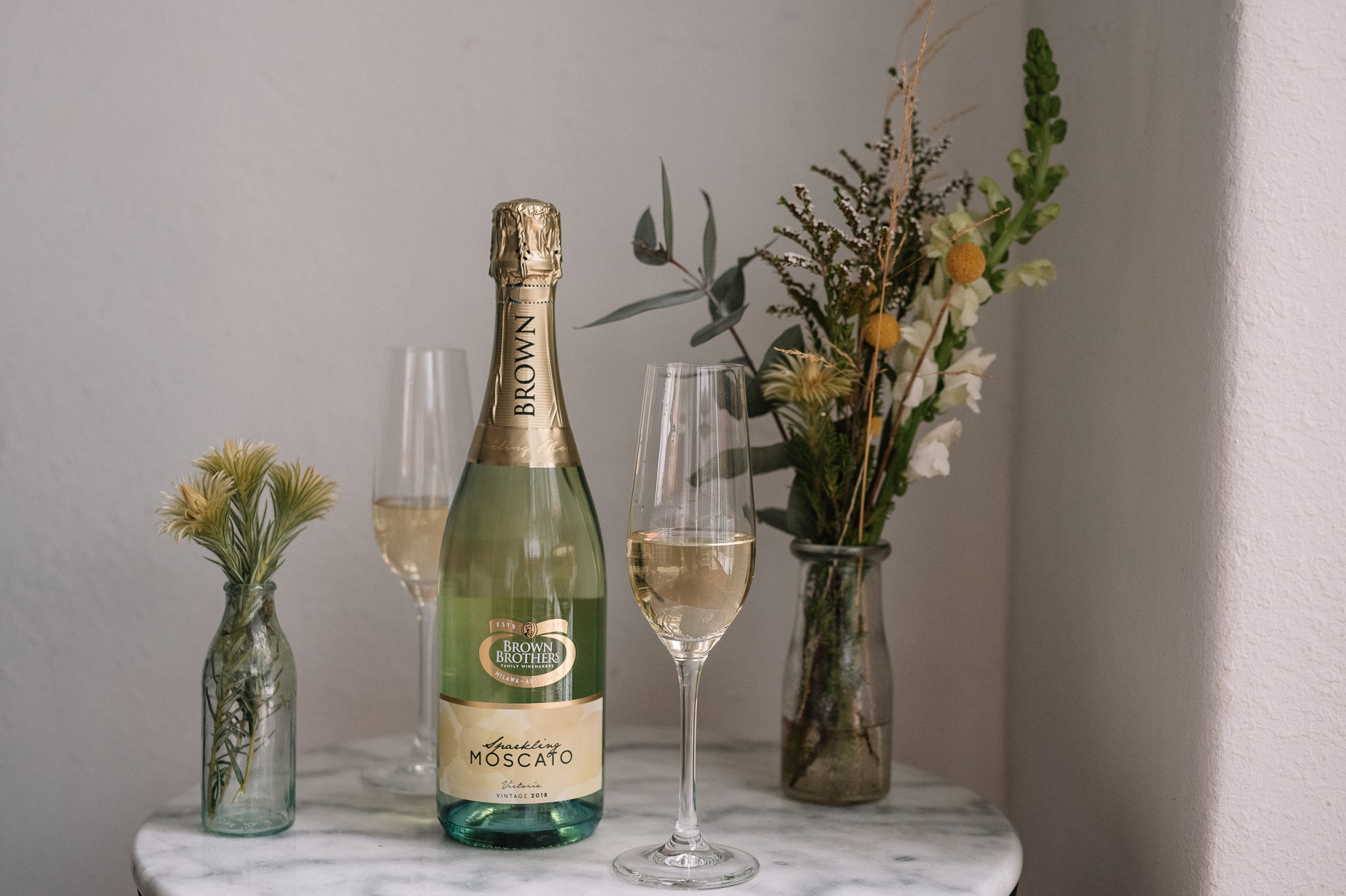 Bottle of Sparkling Moscato on a table with flowers in a vase