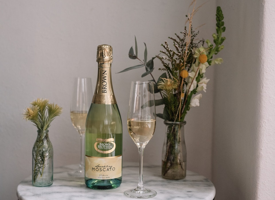 Bottle of Sparkling Moscato on a table with flowers in a vase